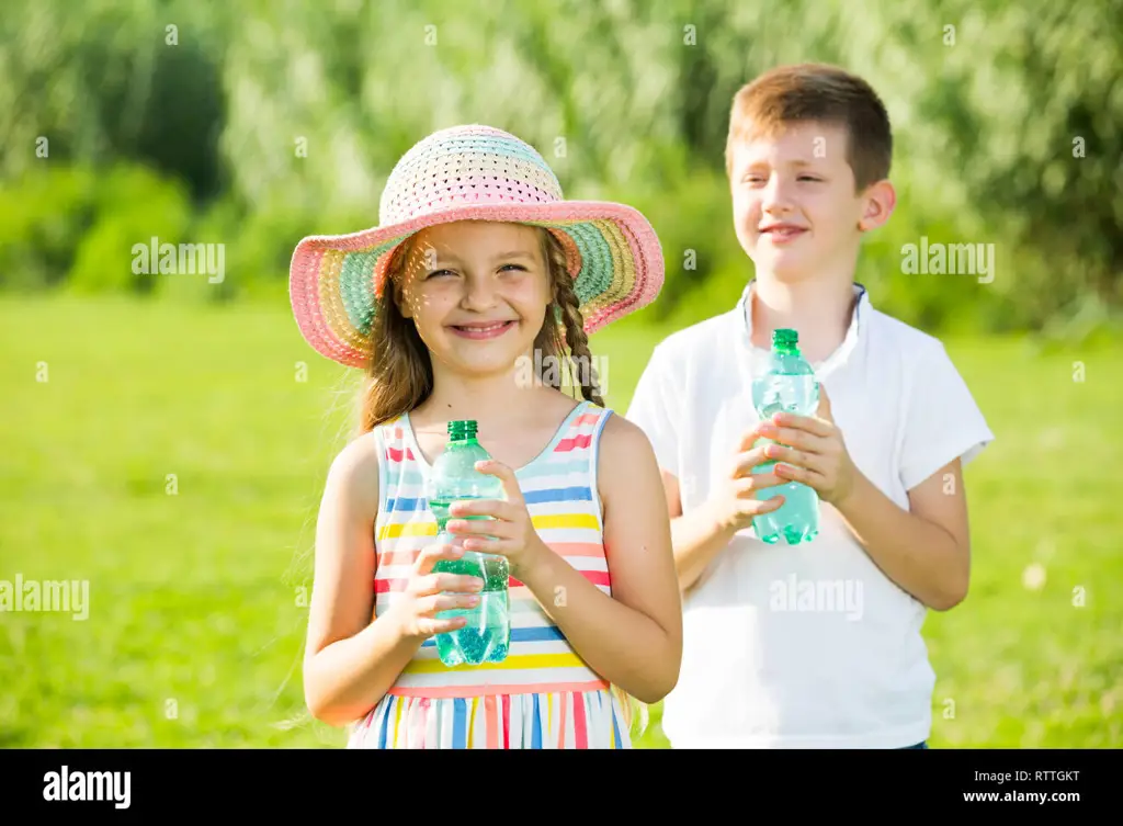 Anak yang bahagia sedang minum dari botol minum karakter hewan