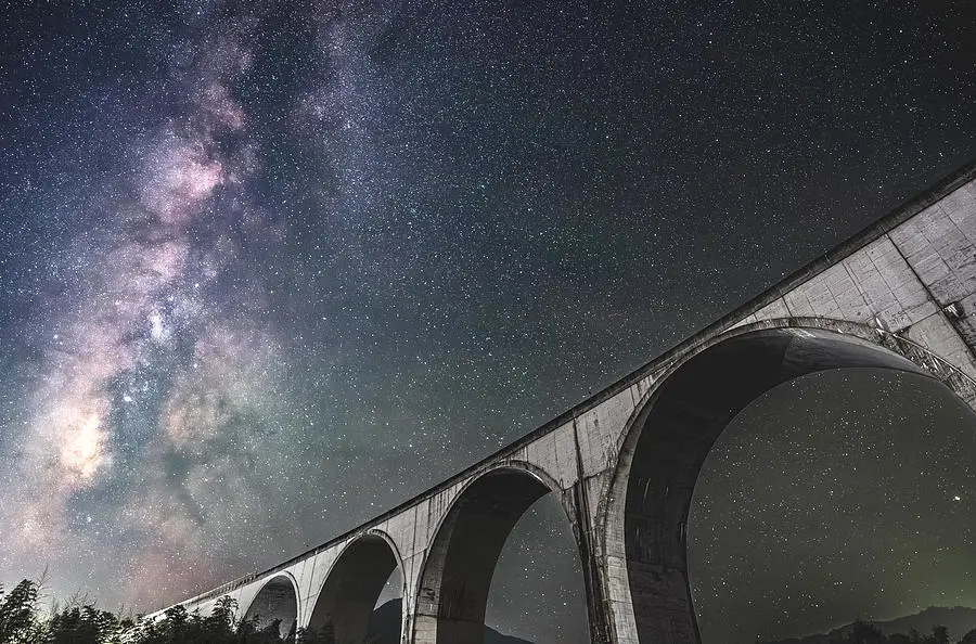 Foto jembatan dengan latar belakang galaksi Bima Sakti yang menakjubkan