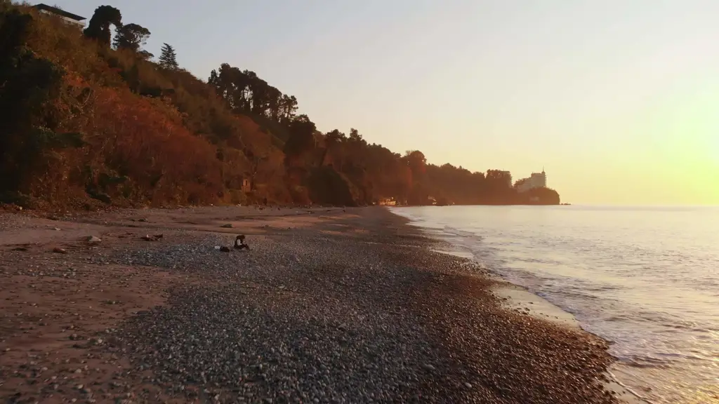 Seseorang duduk sendirian di pantai saat matahari terbenam