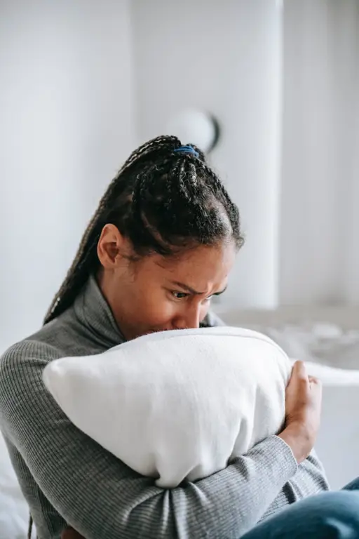 Seorang individu sedang berteriak ke bantal untuk melampiaskan emosinya