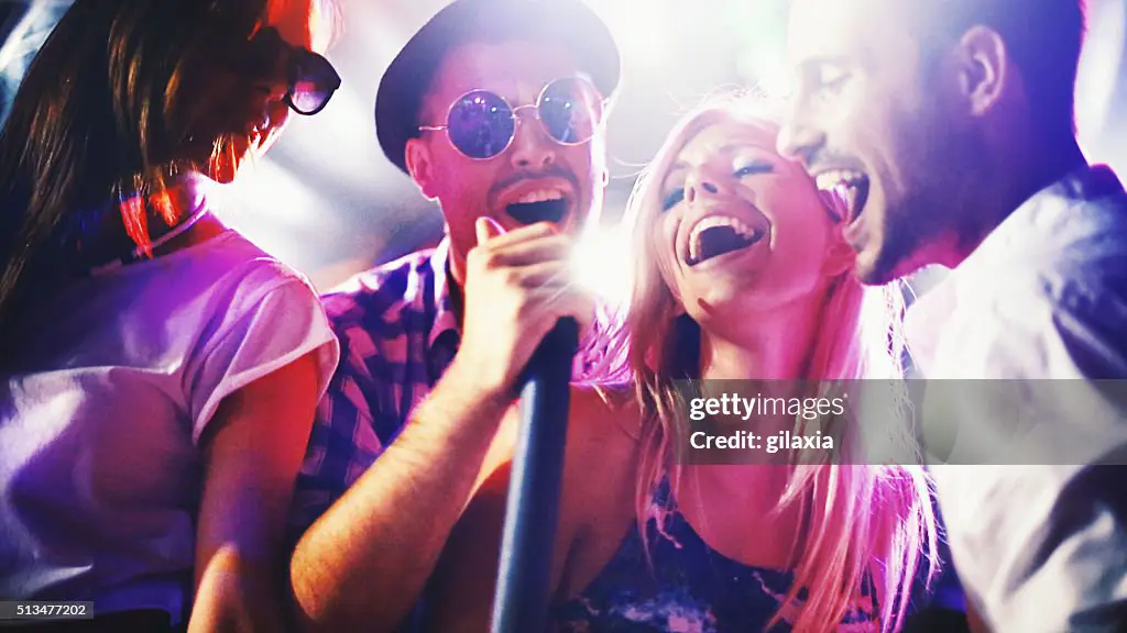 Orang-orang sedang asyik bernyanyi karaoke bersama teman-teman