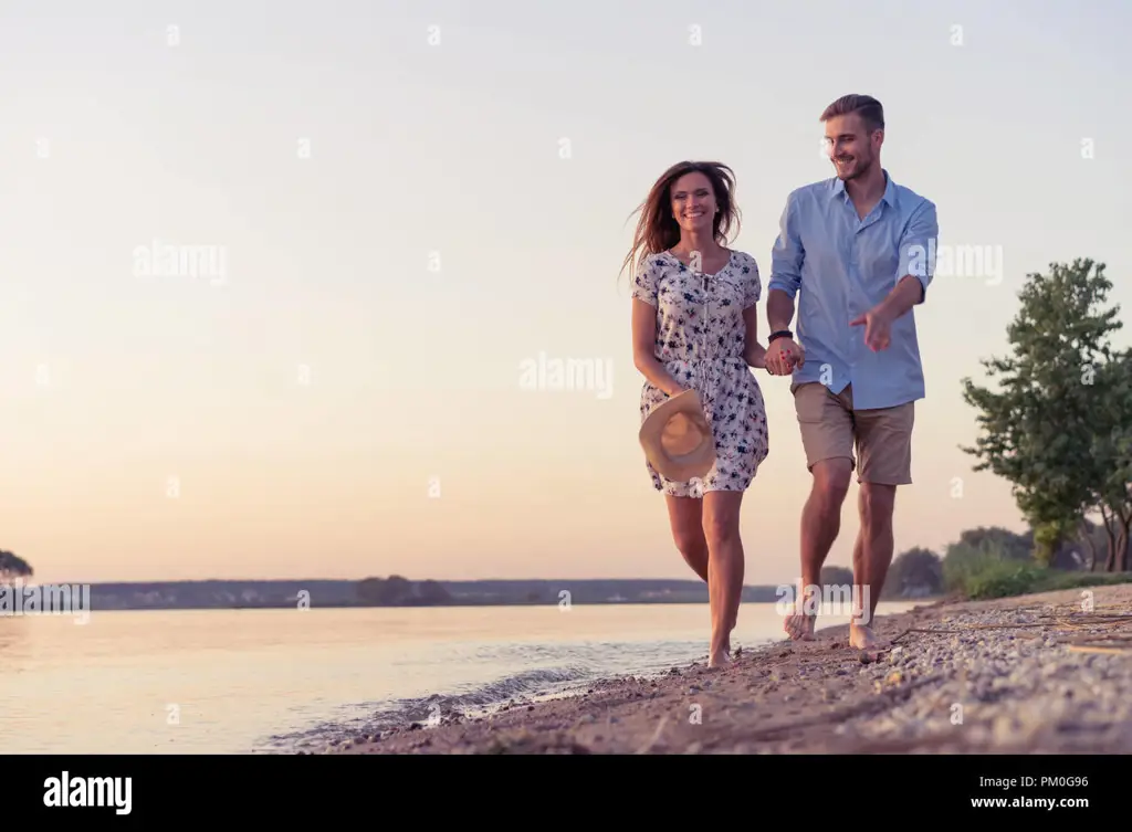 Pasangan berjalan di pantai, melambangkan perjalanan cinta