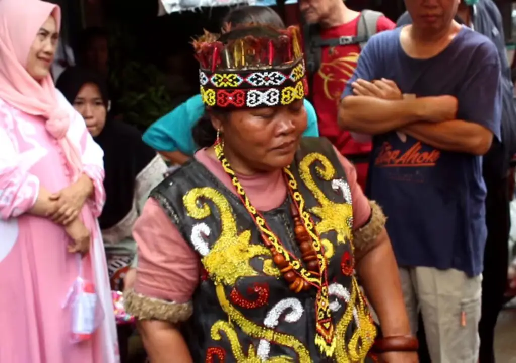 Gambar seorang dukun atau tabib tradisional Indonesia sedang memeriksa pasien