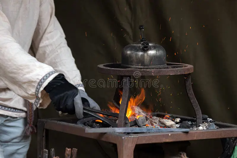 Seorang pandai besi memanaskan besi hingga arde