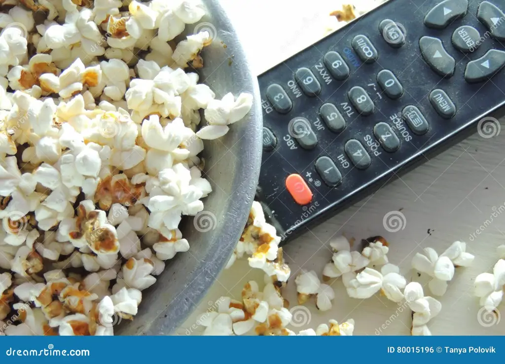 Gambar popcorn dan remote control di depan televisi