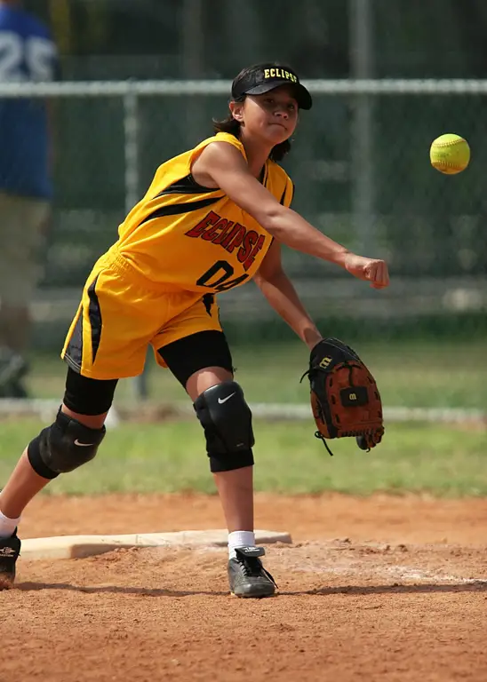 Seorang pelempar softball wanita sedang melempar bola